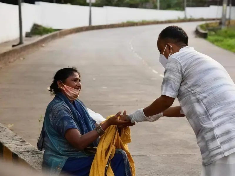 An ISKCON volunteer handing food to an elderly woman on the roadside